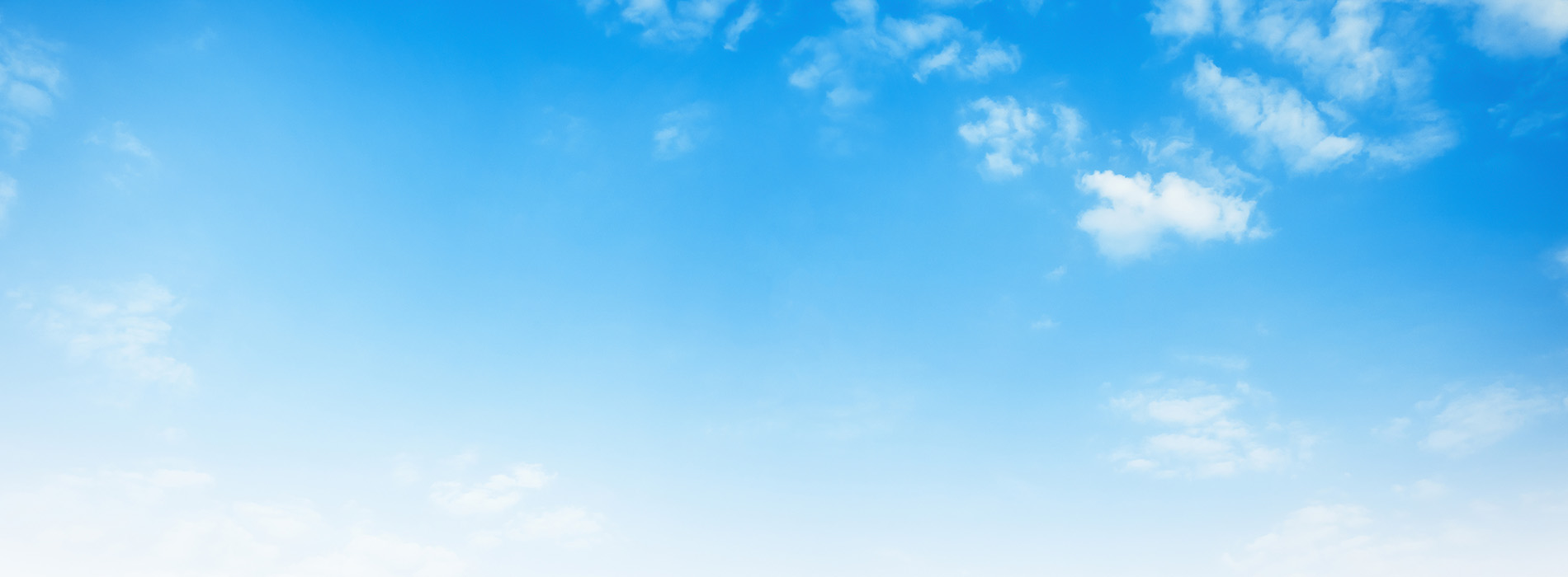 The image shows a clear blue sky with a few wispy clouds and a horizon line where the sky meets the land.